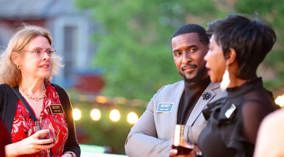 Group of Purdue Global employees talking at an event