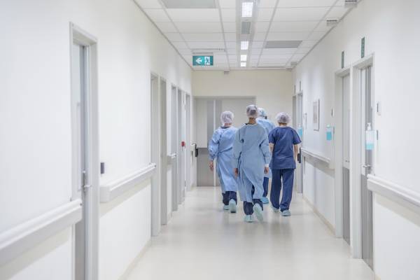A group of nurses walk down a hospital hallway.