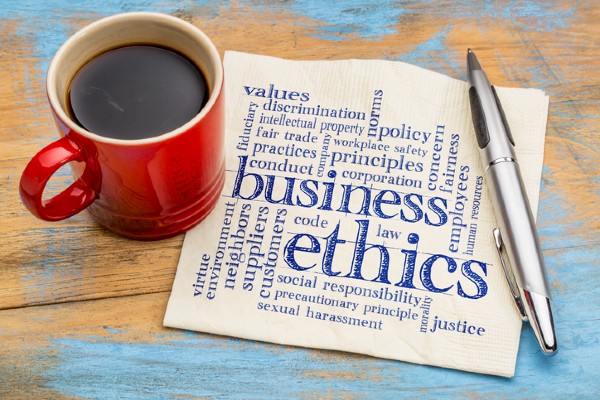 A coffee cup sits next to a word cloud representing “business ethics.”