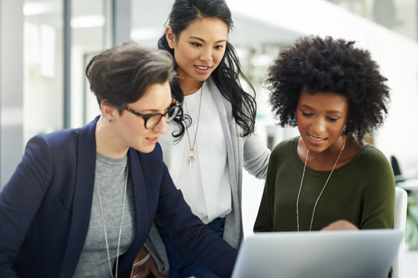 Three women look at a laptop