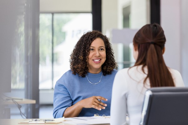 An HR professional talks with a coworker in an office.