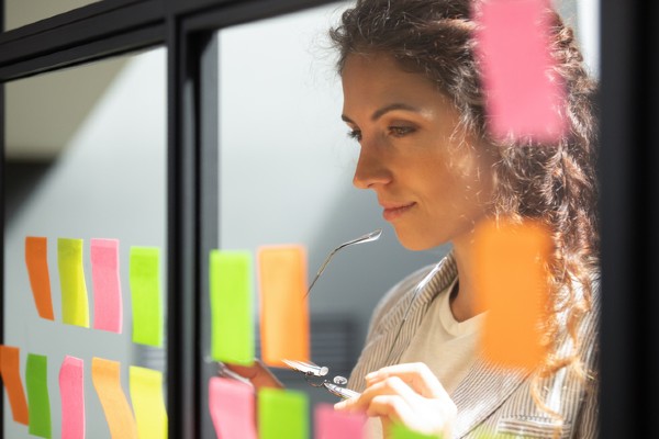 A woman ponders a series of sticky notes with career ideas on them.