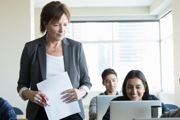 A woman holds a piece of paper and looks at a student