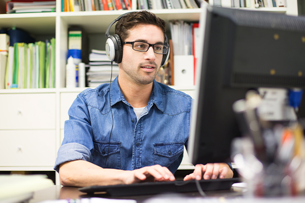 An instructional design and technology professional sits at a desk in front of a computer monitor.