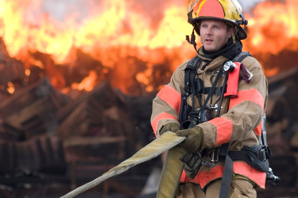 A fireman stands in front of a fire