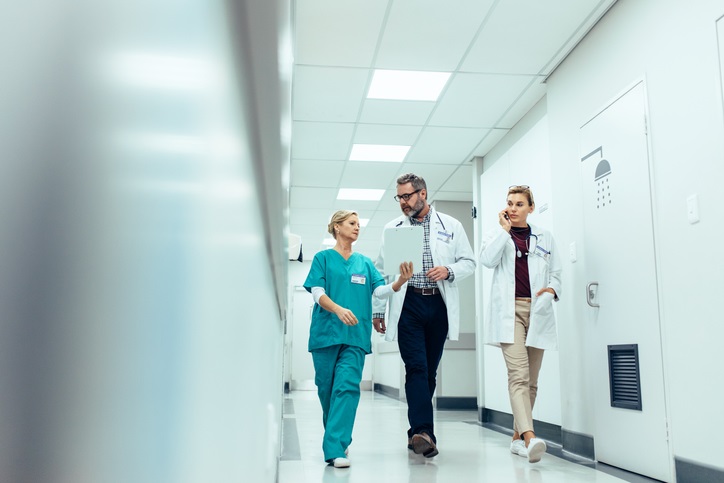 help with nursing essays A nurse talks to two health care workers while walking