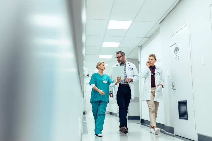 A nurse talks to two health care workers while walking