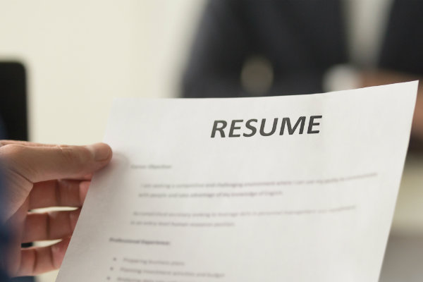 A paper resume in a person's hand