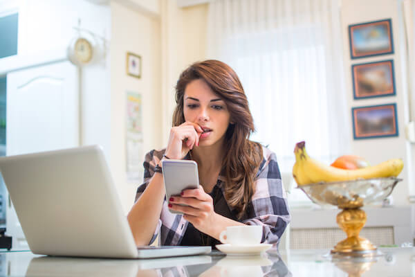 College student looking at laptop and cell phone