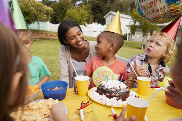 A child sits on a woman's lap at a birthday party