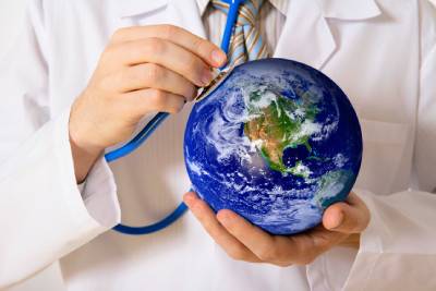 A person holds a stethoscope to a globe