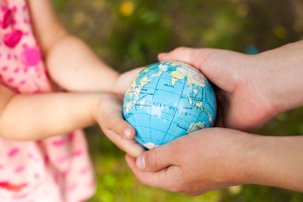 A child and an adult hold a small globe in their hands