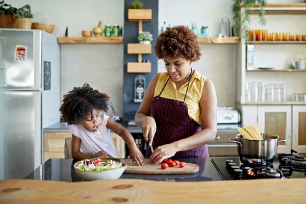 A woman and her child prepare a healthy salad in a kitchen.