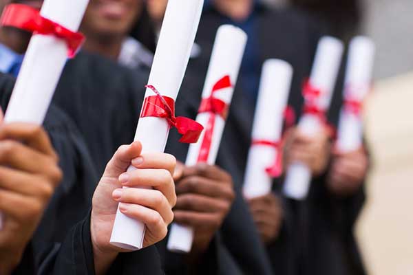 A group of graduates hold diplomas in their hands
