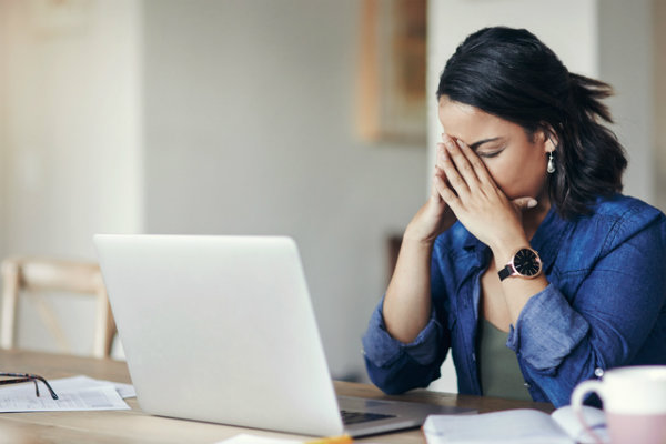 30-something woman sitting at her laptop, obviously distressed