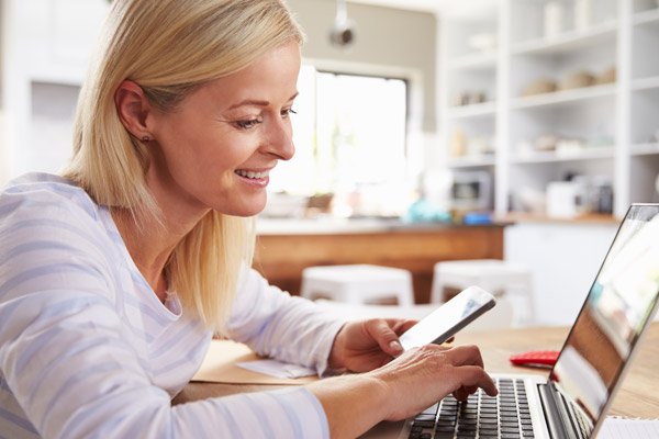 A woman smiles while looking at a laptop