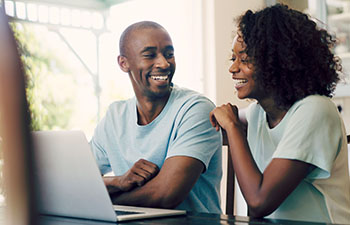 Man and woman sitting in front of laptop looking at each other