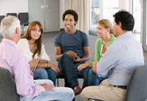 A group of people sit in a circle during a group therapy session.
