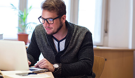 man with glasses working on computer