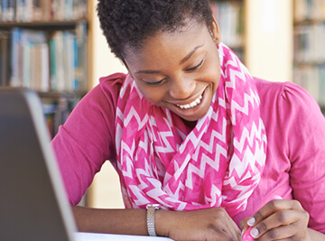 Woman sitting in front of laptop happy to get transfer credits
