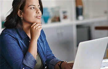 Woman on a laptop with her hand to her chin
